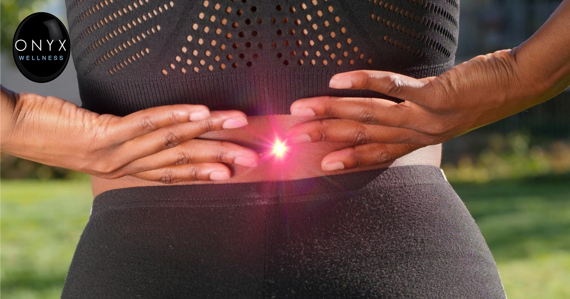 Woman in running clothes holding her lower back in pain while standing outdoors