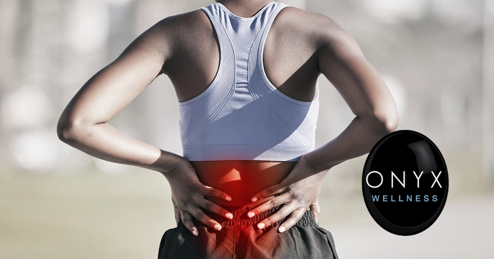 woman holding her aching lower back while wearing exercise clothes