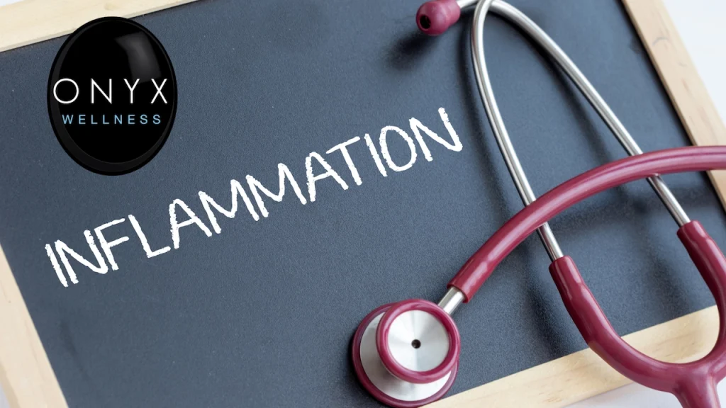Close-up of a chalkboard with the word "Inflammation" written in white chalk, a stethoscope resting across it