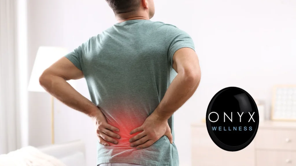 Man using both hands to hold or massage his lower back, which is highlighted in red to represent inflammation and pain